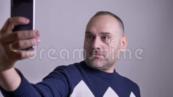 中年白种人男性在电话中自拍并做出不同的面部表情的特写镜头视频的预览图