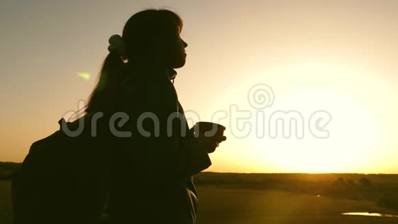 女孩旅行者站在山顶喝着热水瓶里的玻璃咖啡Hiker女孩喝热茶视频的预览图