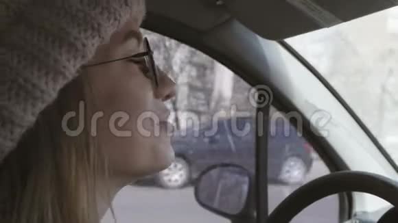 年轻开朗的女人开车戴着粉红色的帽子和眼镜女孩一边开车一边和乘客说话转身视频的预览图