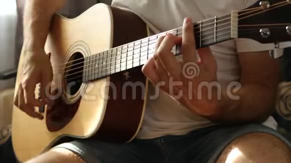 这位音乐家在黄色的吉他特写镜头上奏出快速的节奏一束光线落在手指和脖子上视频的预览图