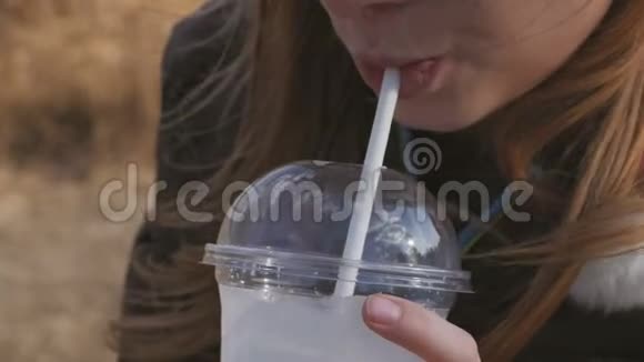 一个年轻的女孩通过吸管从塑料玻璃喝奶昔视频的预览图