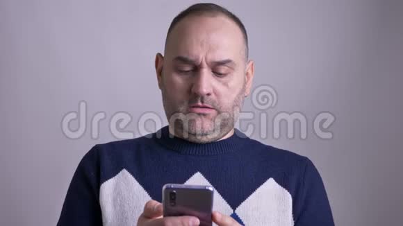 中年白种人男性的特写镜头在手机上浏览看着镜头开心地笑着视频的预览图