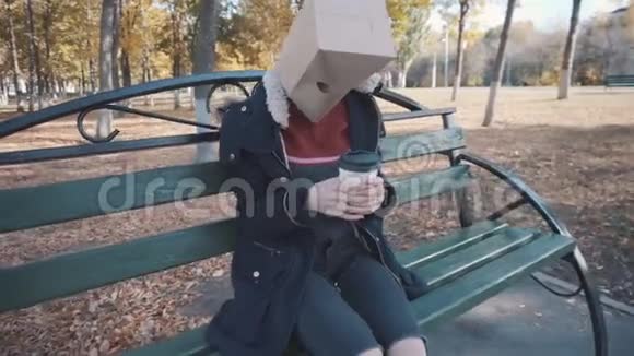 那个头上戴着包裹的女孩坐在一张长凳上喝着一杯咖啡穿夹克的女孩视频的预览图