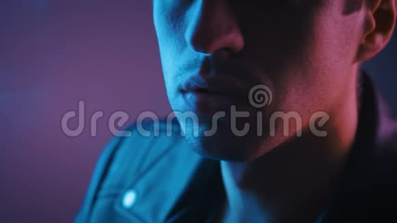 男性的肖像穿着皮革黑色外套在蓝色和粉红色霓虹灯背景上吸烟或电子香烟视频的预览图