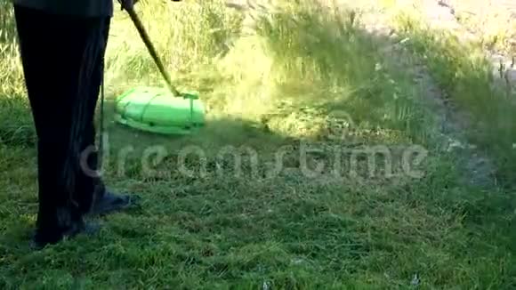一个人在户外用手持割草机割草园丁在院子里工作视频的预览图