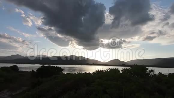 夕阳西下一片海洋泻湖上一片戏剧性的天空的全景地平线上群山的黑色轮廓视频的预览图