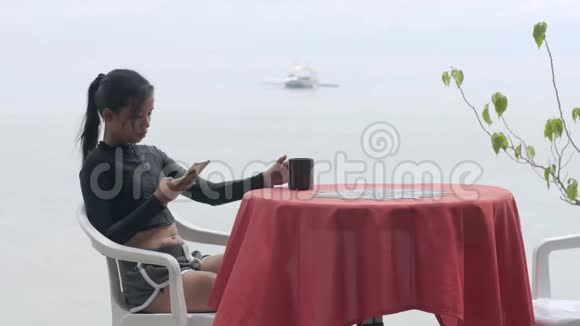 度假的年轻女子在海边的咖啡馆里喝杯咖啡视频的预览图