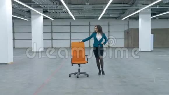 一个穿着办公室衣服的女人正高兴地在大厅里转动一把滚动的椅子视频的预览图