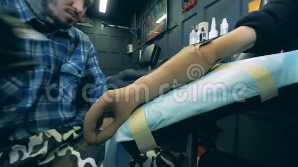 男艺术家正在他的工作室里做一个合成手臂上的纹身视频的预览图