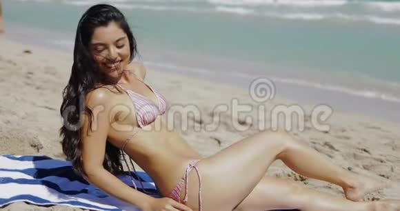 穿比基尼的漂亮女孩坐在沙滩上视频的预览图
