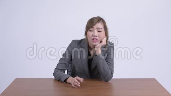 年轻有压力的亚洲女商人看着无聊的办公桌视频的预览图