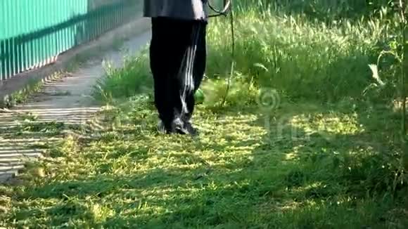 一个人在户外用手持割草机割草园丁在院子里工作视频的预览图