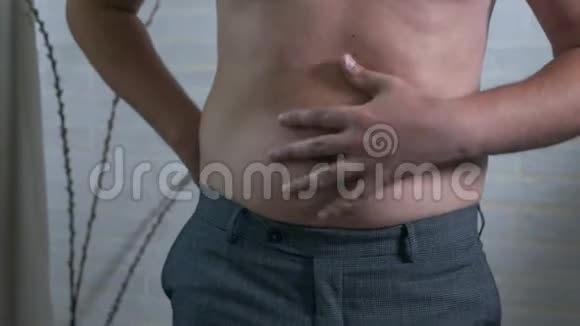 特写男性胃部超重一个赤裸着胖肚子的年轻人摇着肚子上的脂肪褶肥胖健康视频的预览图