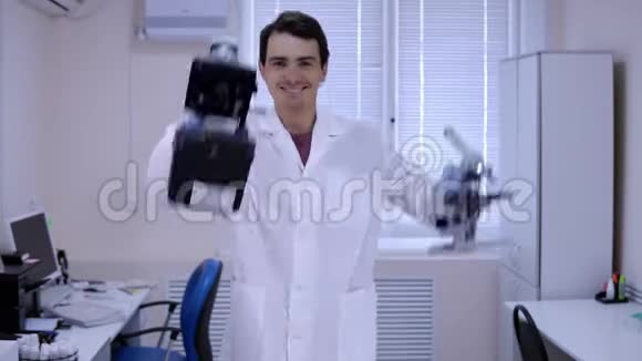 年轻的实验室技术人员手里拿着显微镜在实验室跳舞视频的预览图