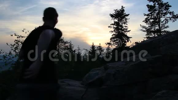 年轻的站着在捷克风景中的石岩上庆祝日落时的树木视频的预览图