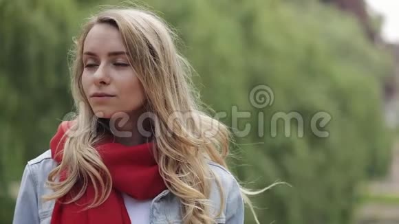 站在城市公园外面戴着红领巾的年轻美女的肖像美丽的女人微笑着看着视频的预览图