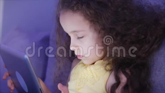 一个高加索可爱的孩子一个小女孩特写一个孩子的夜景一台平板电脑视频的预览图