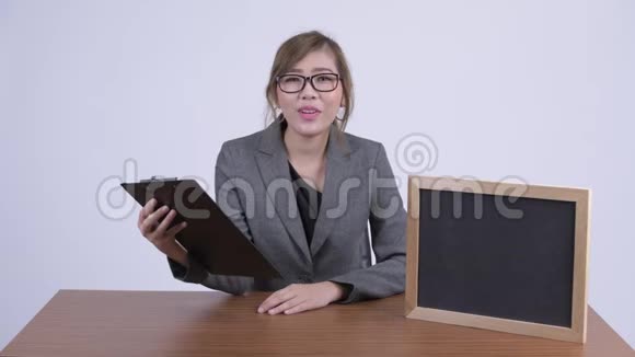 年轻快乐的亚洲女商人在剪贴板上看书视频的预览图