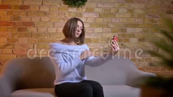 一位年轻可爱的白种人女性的特写镜头她在手机上自拍一边摆姿势一边把头发固定在地上视频的预览图