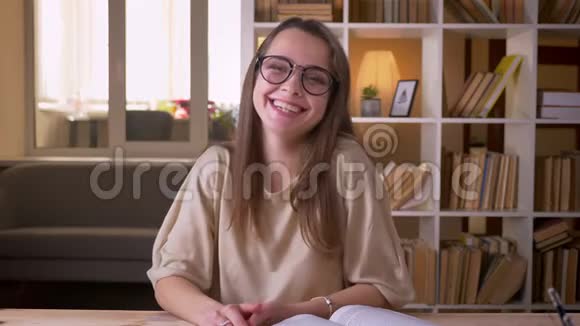 年轻漂亮的白种人女学生戴着眼镜看着镜头在室内愉快地笑着视频的预览图
