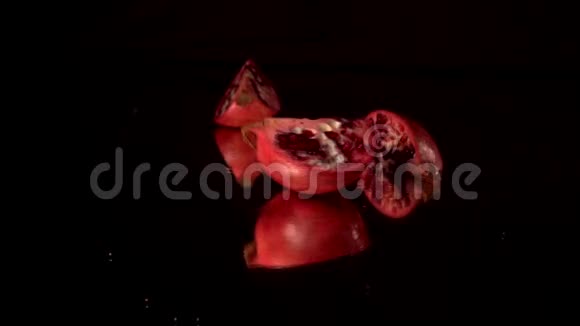 一片鲜红色石榴在黑镜台上旋转黑色背景视频的预览图