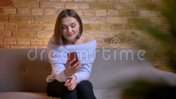 在舒适的室内沙发上打电话的白种人年轻女性的特写镜头视频的预览图
