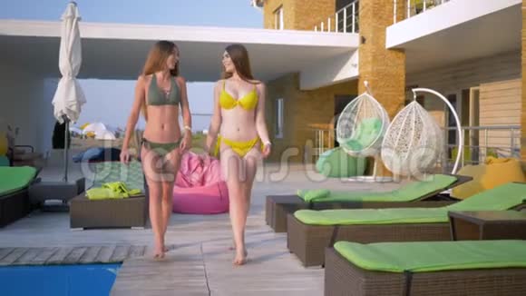 夏日周末在度假村里快乐的朋友女孩们穿着泳装在游泳池附近散步视频的预览图