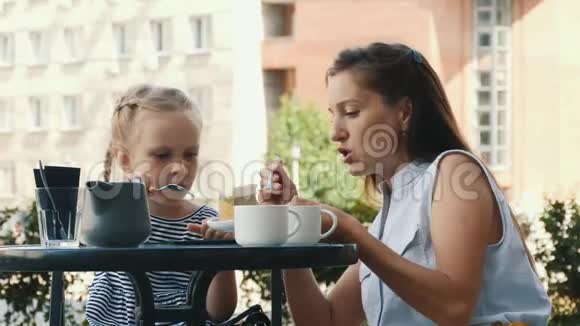 美丽的高加索母亲和小女儿一起在户外咖啡厅吃蛋糕视频的预览图