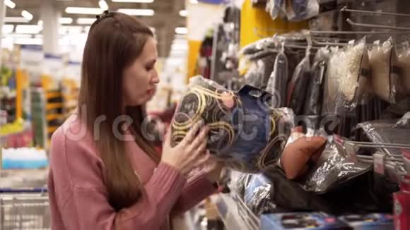 一个年轻的女人在超市为一辆汽车选择一个枕头视频的预览图