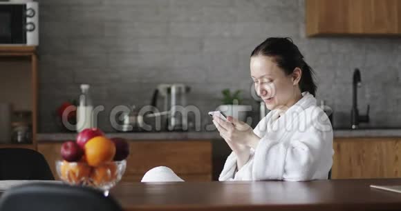 一个穿着白色浴袍的成年女人正在手机上输入一条信息视频的预览图