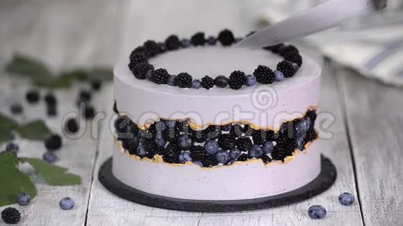 手切块蛋糕紫色美丽的蛋糕上面装饰着浆果黑莓和蓝莓视频的预览图