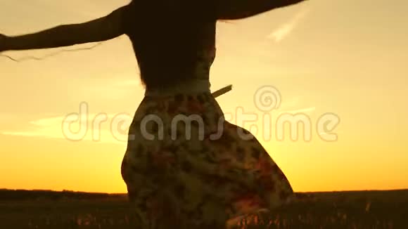 性感的女孩听着音乐在美丽的日落的光线中跳舞戴着耳机的年轻女孩视频的预览图