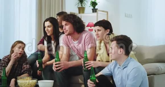 快乐和热情的朋友在电视上看一些有趣的东西喝啤酒享受在一起的时光视频的预览图