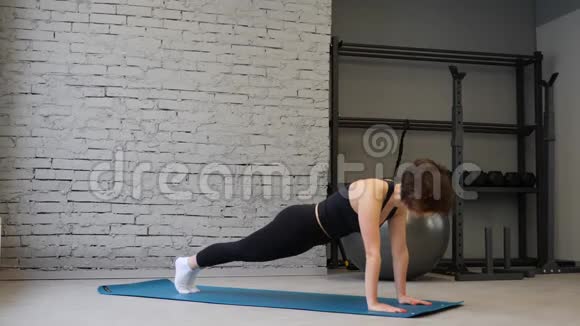 年轻的运动白种人女性在运动服装中保持木板位置同时在健身房锻炼视频的预览图