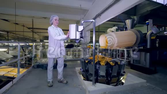 工厂工人用一台机器控制一条带马铃薯薯片的生产线视频的预览图