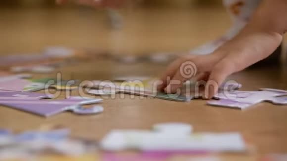 一个小孩子在房间里坐在地板上收集拼图特写孩子手视频的预览图