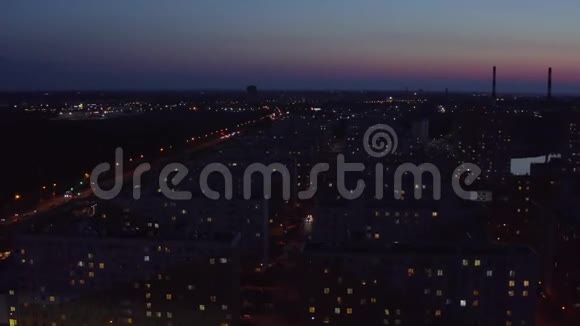 在色彩斑斓的日落天空景观上在黑暗的城市中鸟瞰住宅建筑视频的预览图