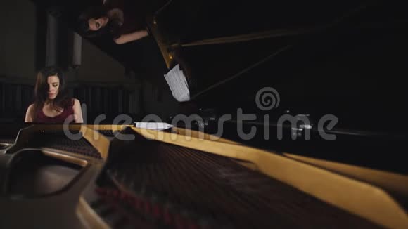女子在音乐厅弹钢琴的总平面图透过敞开的钢琴看女孩视频的预览图