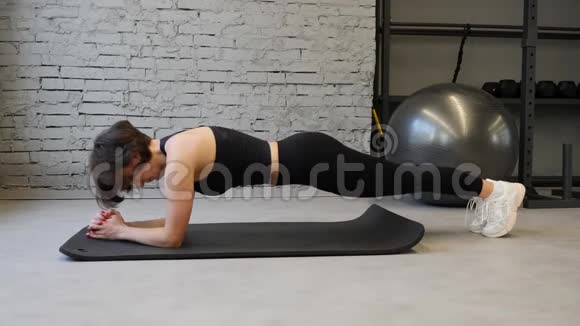 年轻的运动白种人女性在运动服装中保持木板位置同时在健身房锻炼视频的预览图