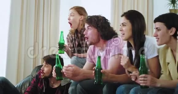 有魅力的成熟人士在观看足球比赛时在电视前用瓶子特写喝啤酒的欢呼声视频的预览图