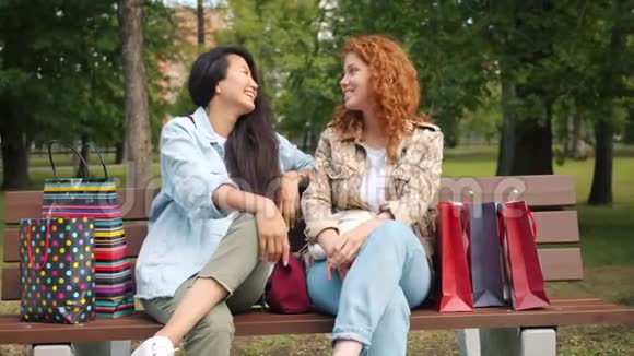 快乐的年轻女性在公园的长椅上谈笑风生视频的预览图