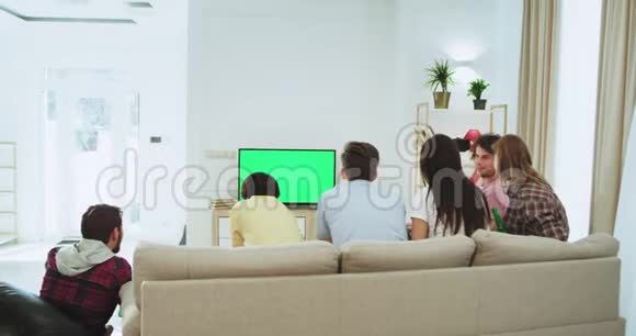 漂亮的朋友在一个大客厅里观看绿色屏幕电视观看足球赛他们支持他们最好的足球视频的预览图