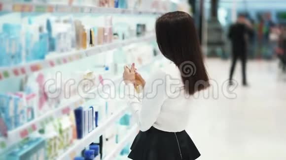 化妆品店里漂亮的女孩选择奶油看货慢动作视频的预览图
