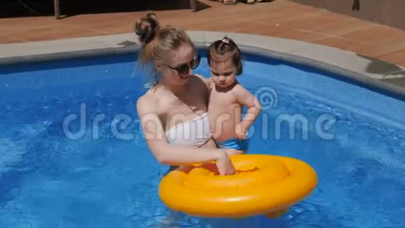 小女孩和妈妈在游泳池里玩充气圈视频的预览图