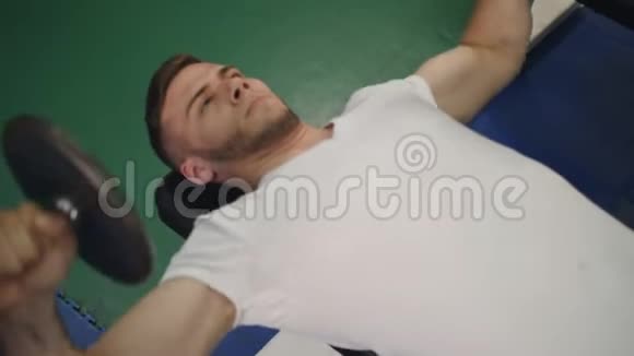 人做运动举起哑铃为二头肌躺在长凳上特写顶部视图视频的预览图