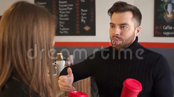 一个拿着一杯咖啡的男人在咖啡店和他的女朋友说话视频的预览图