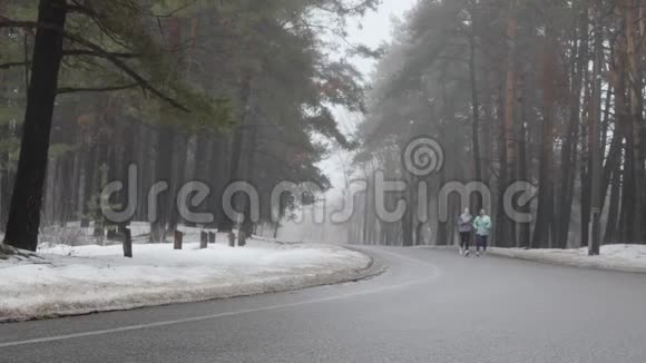 快乐的年长和年轻的高加索女人在冬天的雪地公园里奔跑交谈和微笑前面的静态镜头慢动作视频的预览图