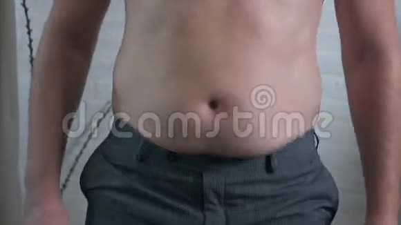 特写男性胃部超重一个赤裸着胖肚子的年轻人摇着肚子上的脂肪褶肥胖健康视频的预览图