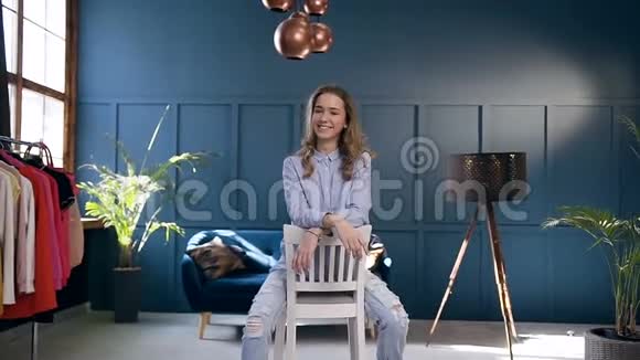 漂亮的年轻女人坐在家里的椅子上视频的预览图