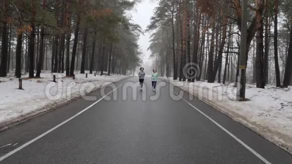 快乐的年长和年轻的高加索女人在冬天的雪地公园里奔跑交谈和微笑前面的静态镜头慢动作视频的预览图